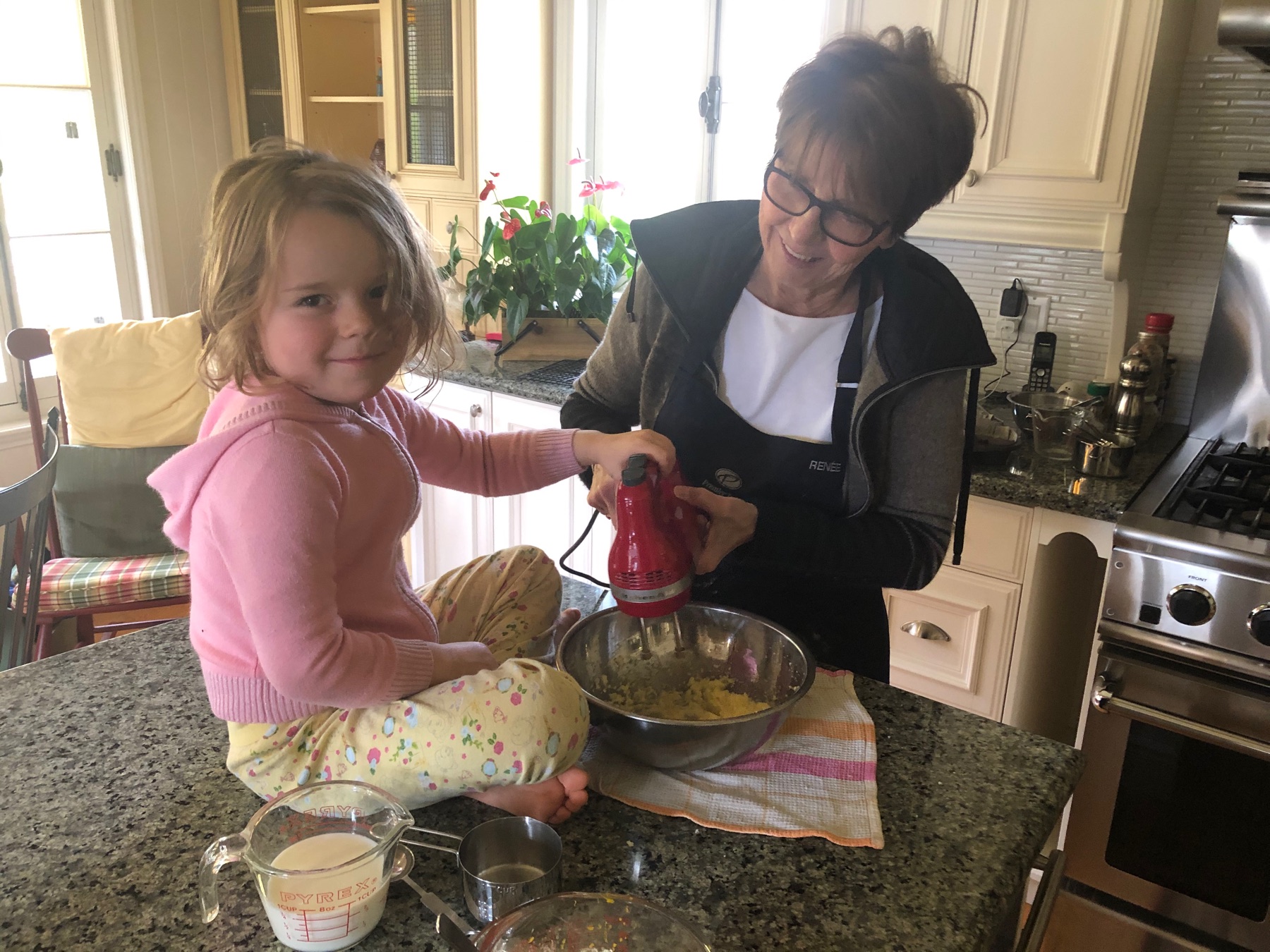 A grandmother and child cooking together at a kitchen counter.